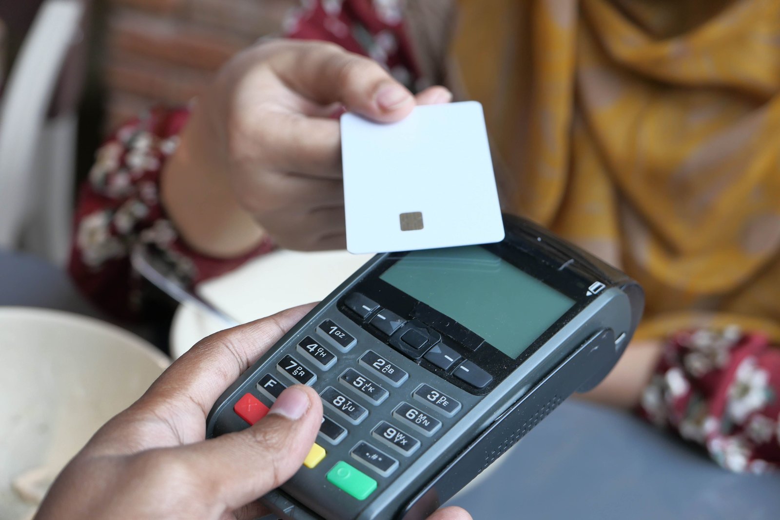 A customer paying at a store counter with a card on a POS terminal